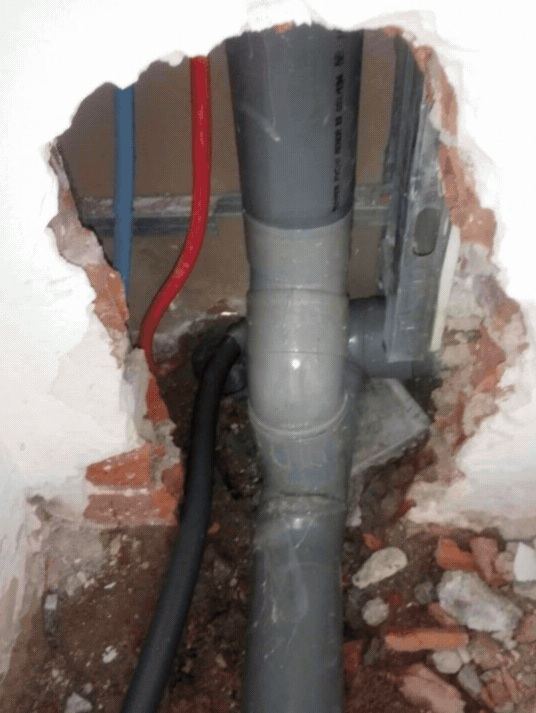 Bajante de PVC gris empotrada en muro de ladrillo con injerto en T